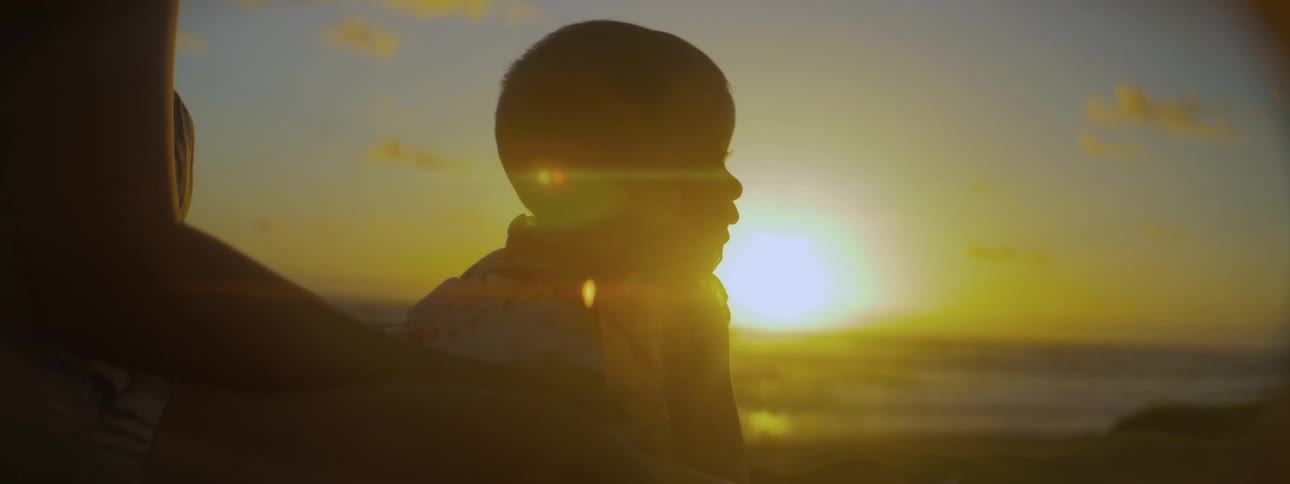 Child looking down at the beach at sunset