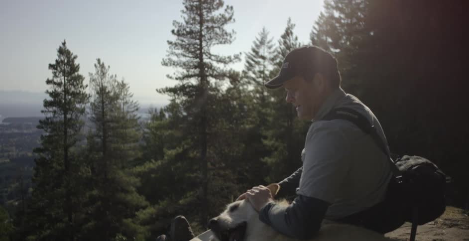 Man petting a dog in the forest