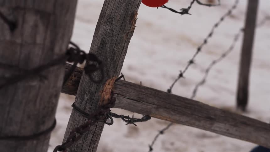 A man begins repairing a wire fence