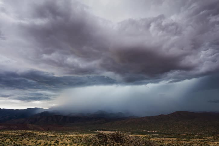 Rain clouds moving over hilly plains