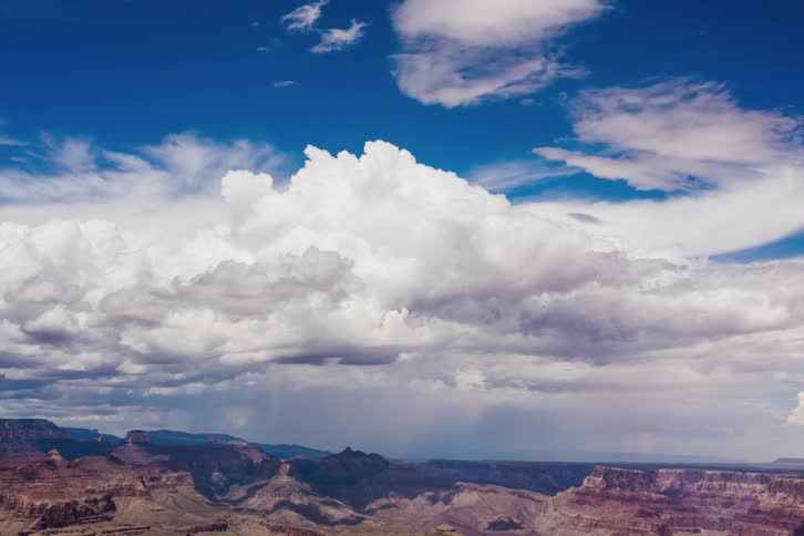 Storm clouds billow and move across a canyon