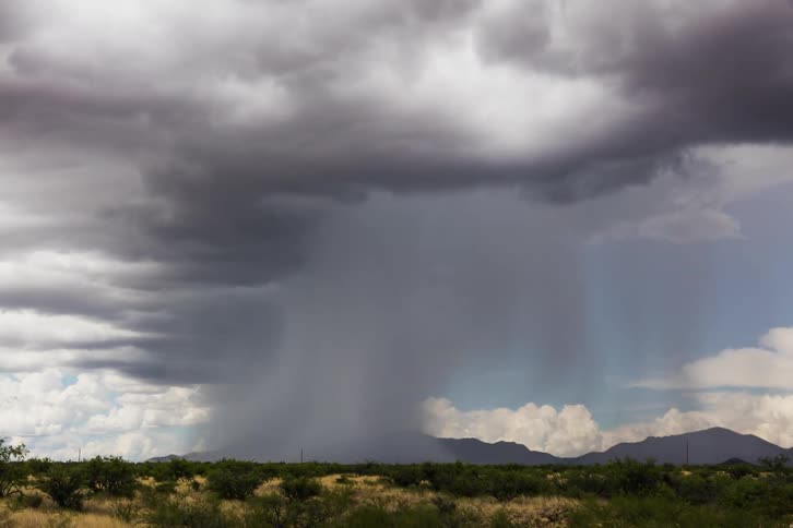 Rain clouds moving over hilly plains