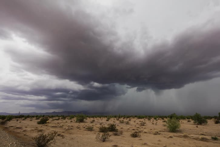 Storm clouds form and drop rain over a plain
