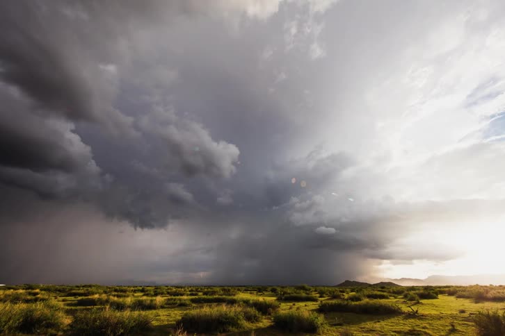 Storm clouds form and drop rain over a plain