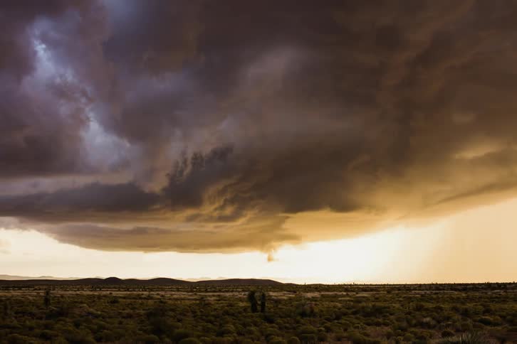 Storm clouds gather and circle over a field