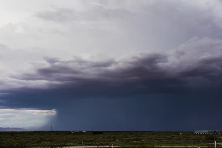 A large storm is running in the distance pouring rain all over