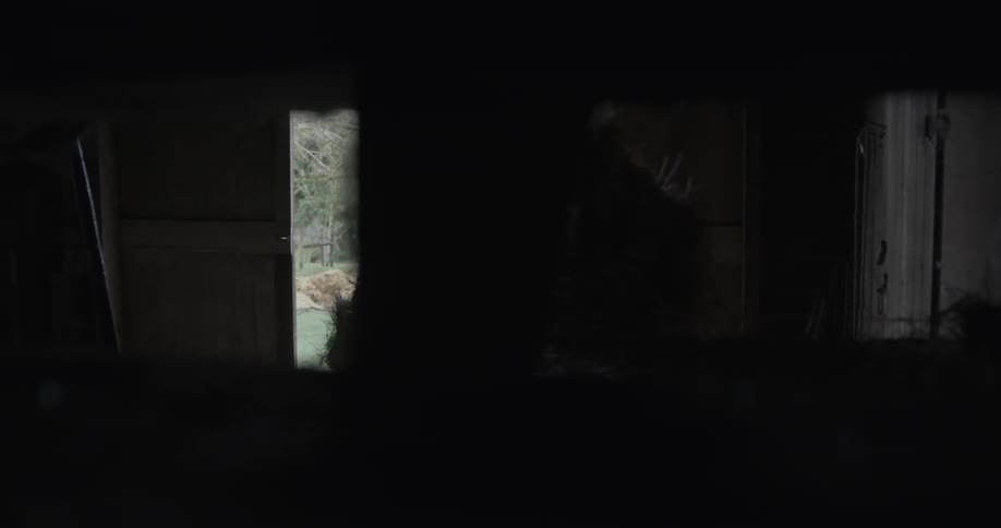 A rancher is pulling a bale of hay from a stack in a barn