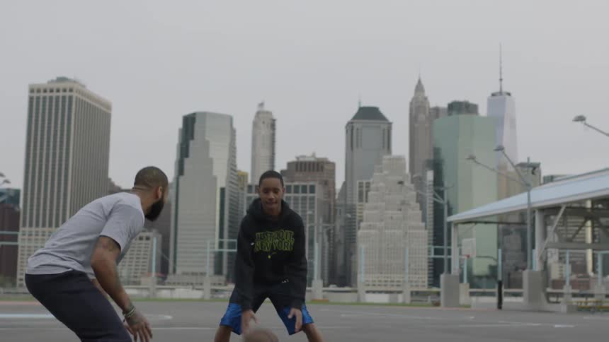 Two men play basketball on a city court