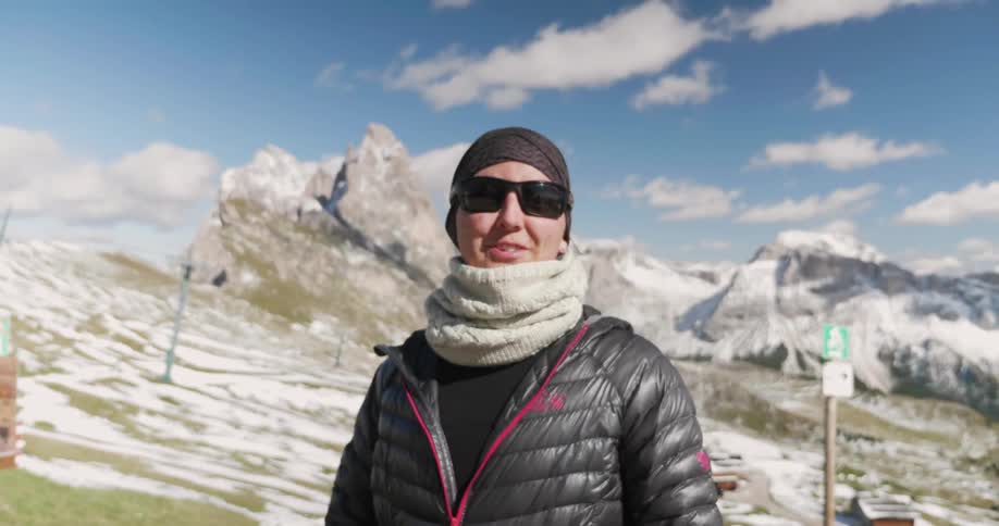 A person with poles in their hands talking and pointing at a mountain