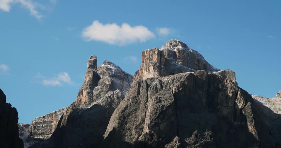 Sparse clouds hang over a stone mountain