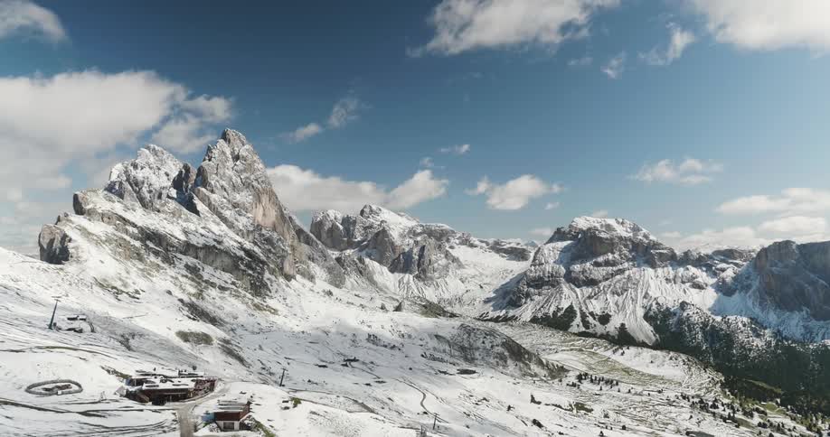 Large snow covered mountains with the clouds moving in the background