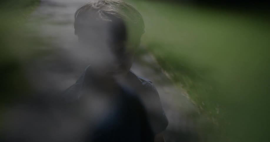 Boy stands outside on a sidewalk at night