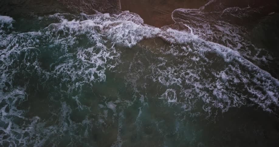 Waves roll onto a beach at dusk