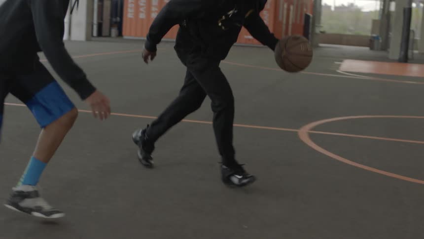 Two people playing basketball inside a building