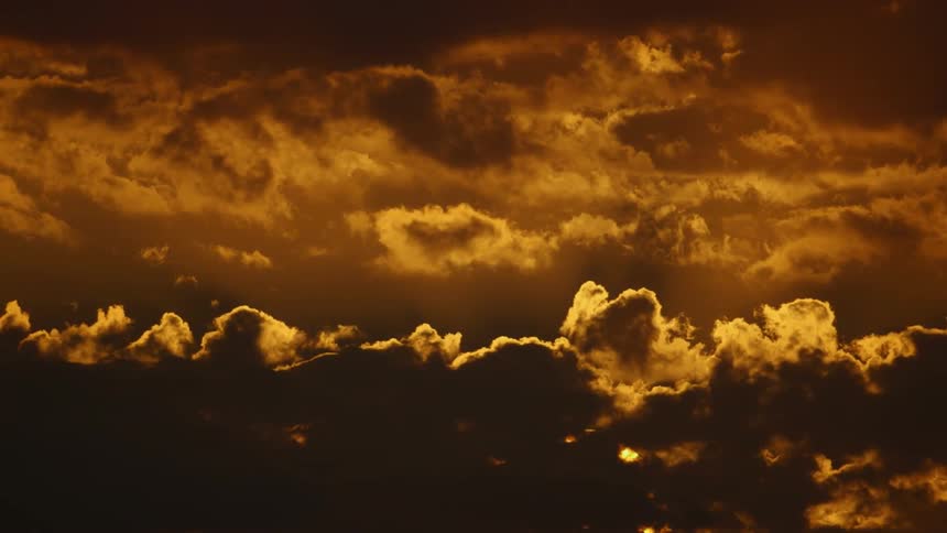 Sun sinking behind fluffy clouds