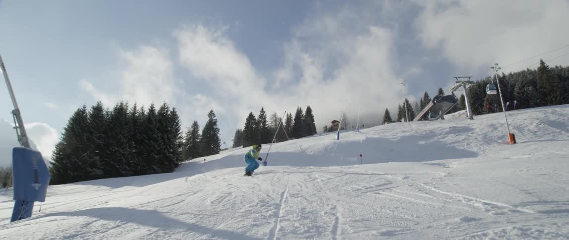 Man snowboarding down a hill jumps over a small rise