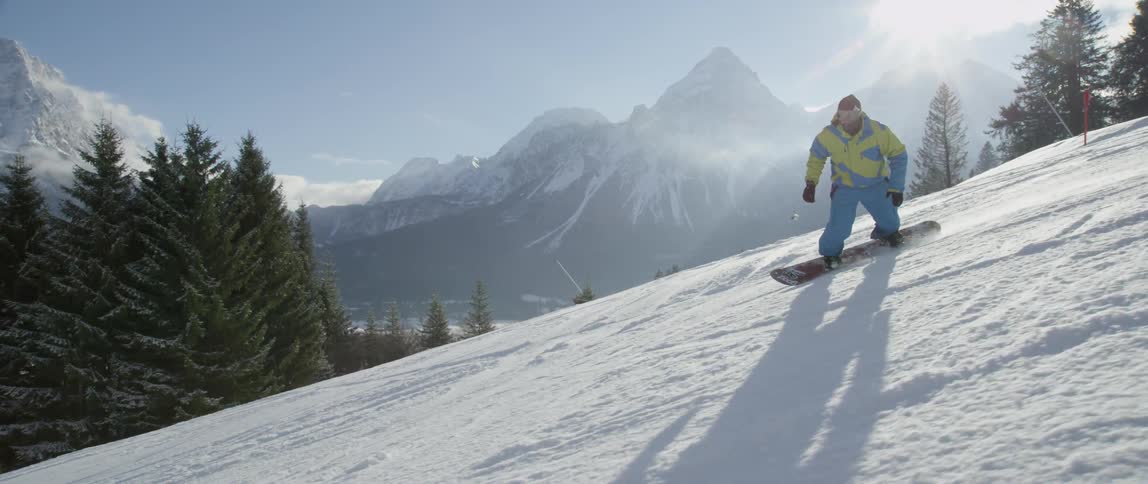 A snowboarder rides down a slope