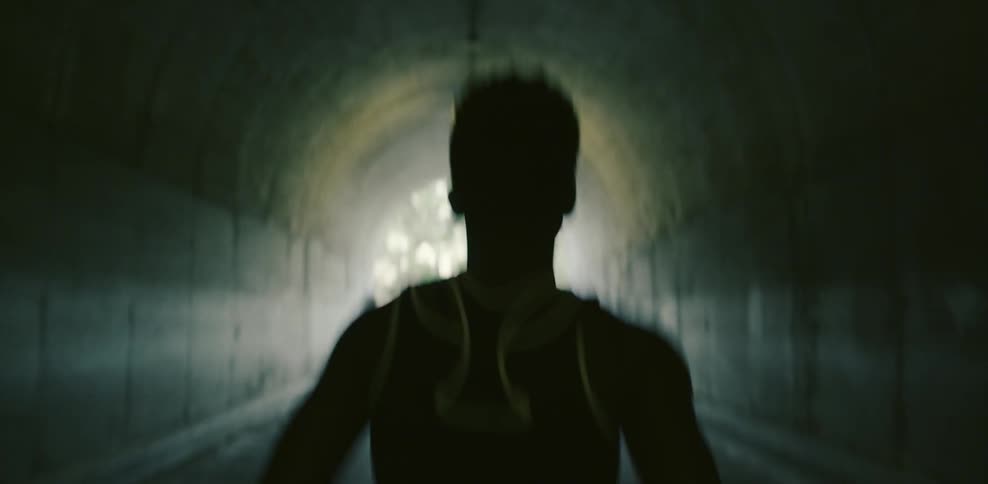 A female athlete is jogging through a tunnel