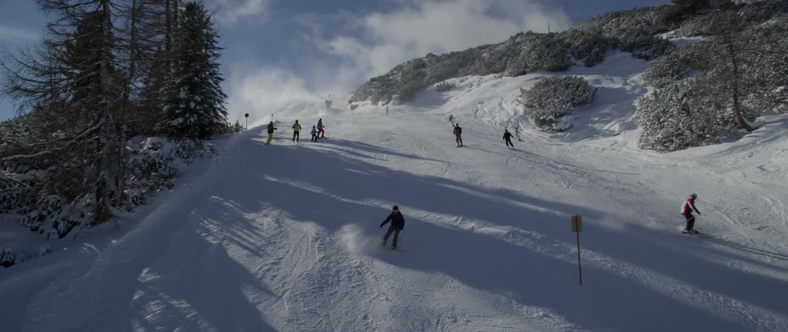 People snowboard down a hill