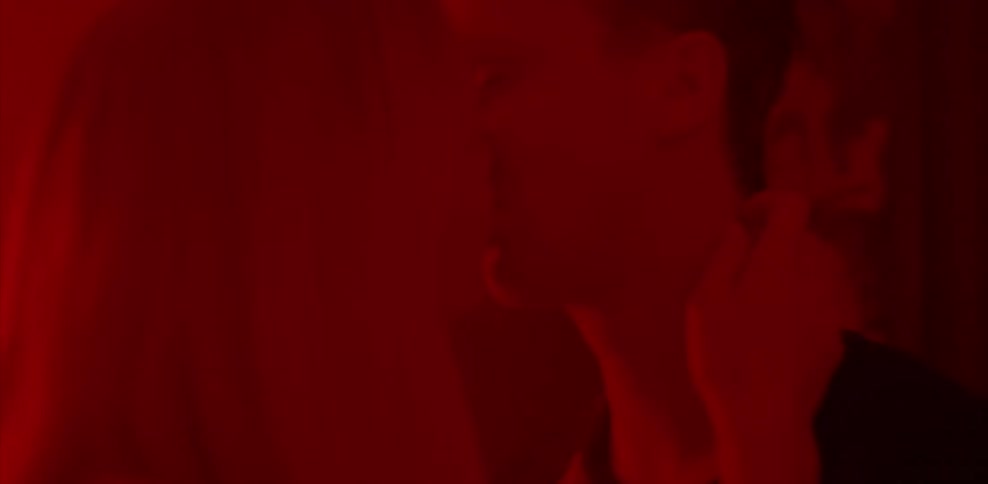 A man and woman are standing and making out in a room
