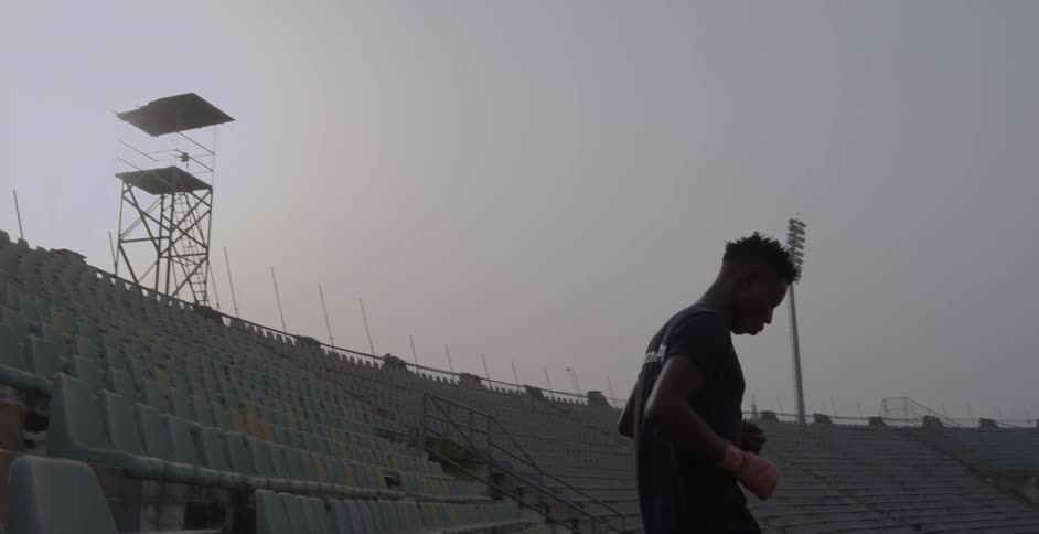 A young man jogs down stairs in a stadium