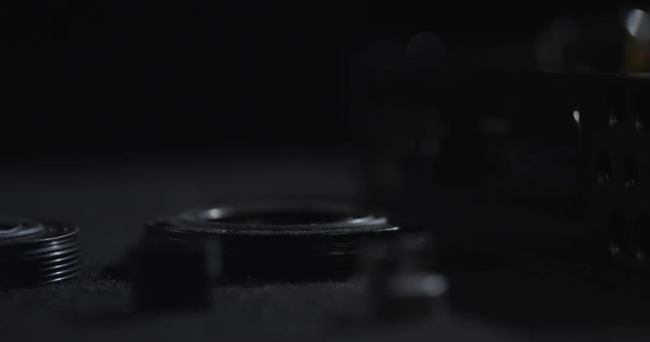 Pieces of a machine are sitting lined up on a surface in a dimly lit room