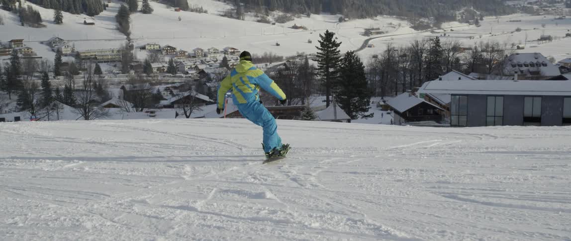 A snowboarder rides down a slope