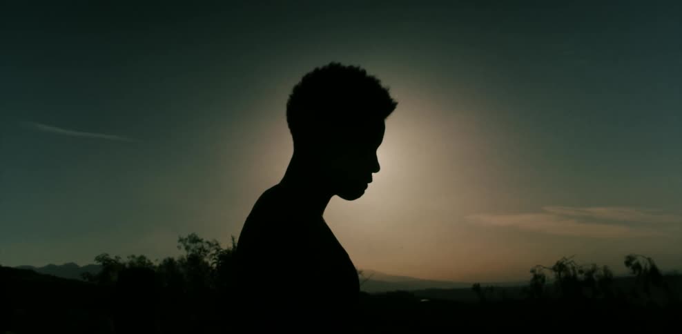 A man stands in front of the sun at dusk