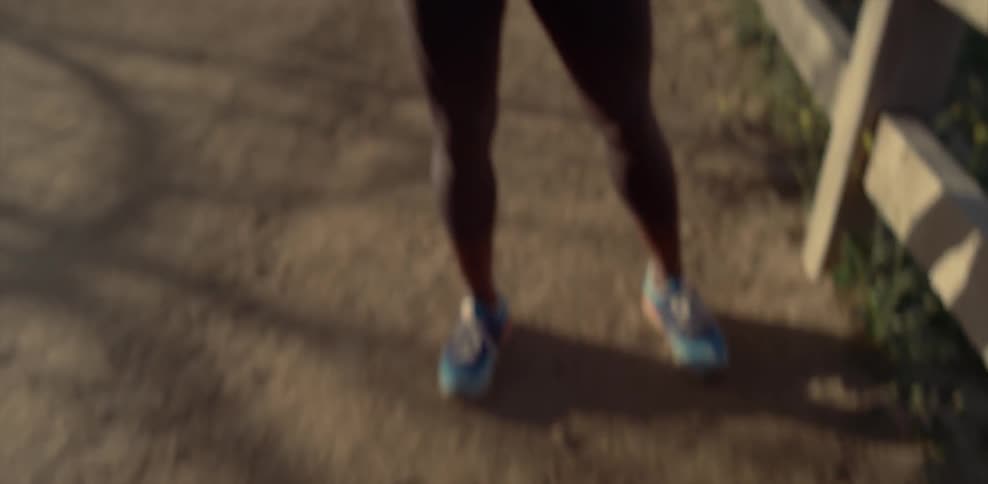 A female jogger is catching her breath as she stands on a dirt path during the day