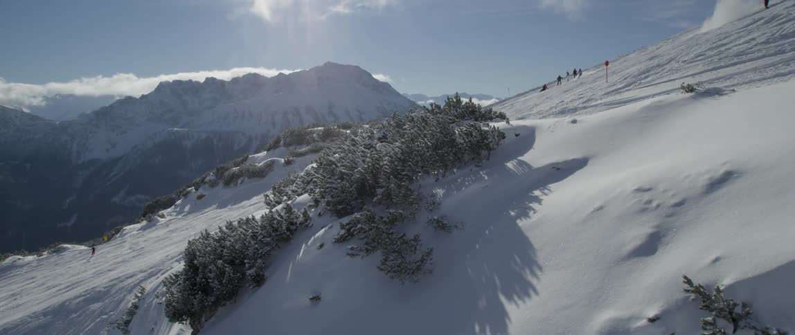 Skiers ride down a mountain on a sunny day