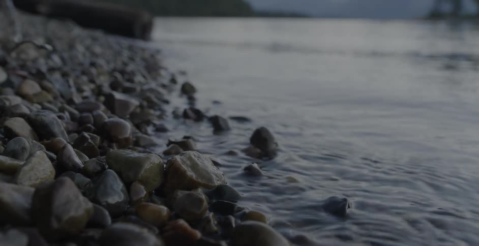 Pebbles on a beach are lapped by waves