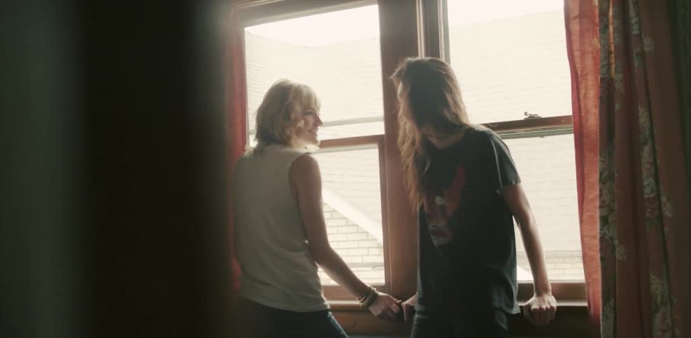 Two women talk in front of some windows