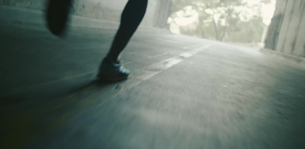 Person jogs through a tunnel out onto a sunny street
