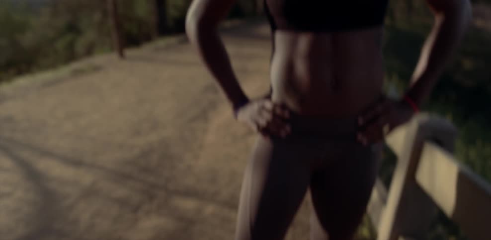 A female athlete is paused on a path in a natural setting