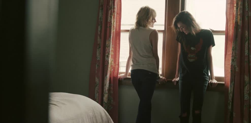 Two women stand next to windows