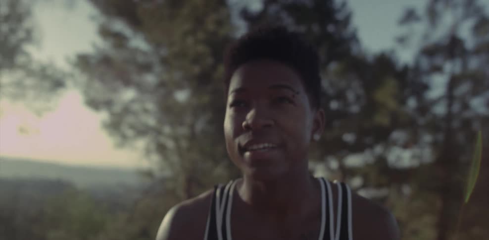A female athlete smiles as she rests in a natural setting at dusk