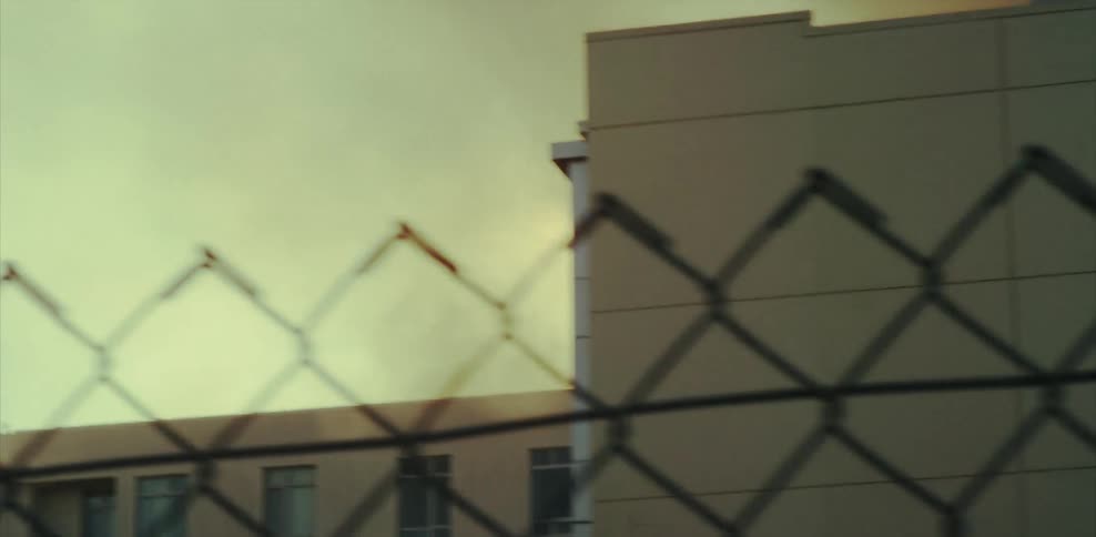 Smoke from a fire rises beyond a building during the day