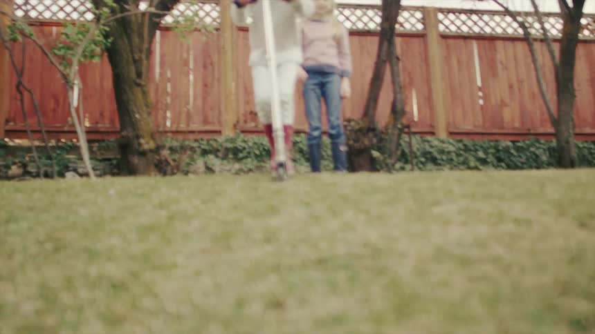 Two children play in a fenced in yard