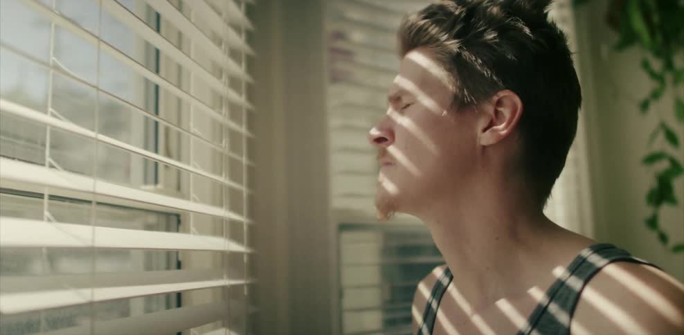 A man closes his eyes near a window