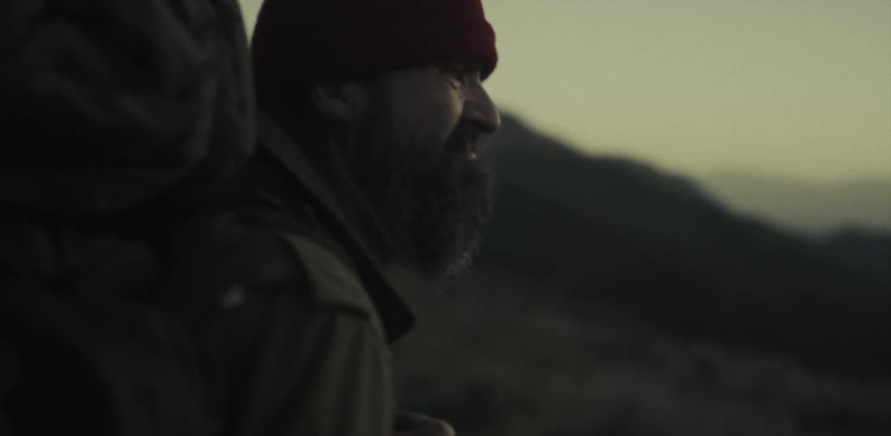 Man looking out at a hilly landscape