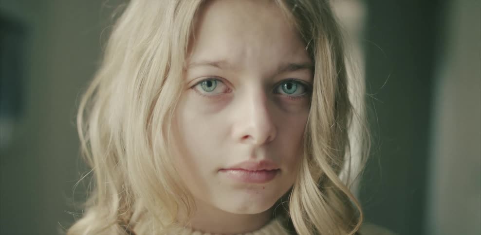 A blonde haired woman stares out looking sad