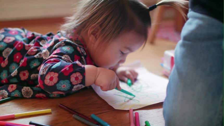A child is coloring on the floor