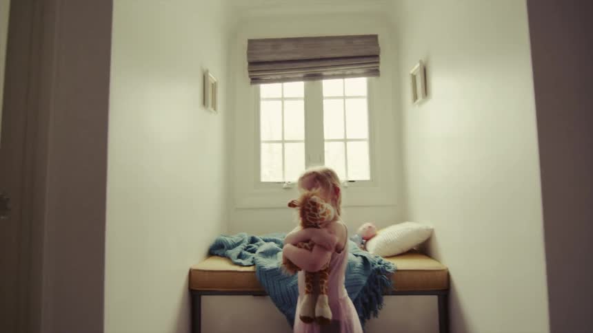 A small girl hugs a stuffed giraffe