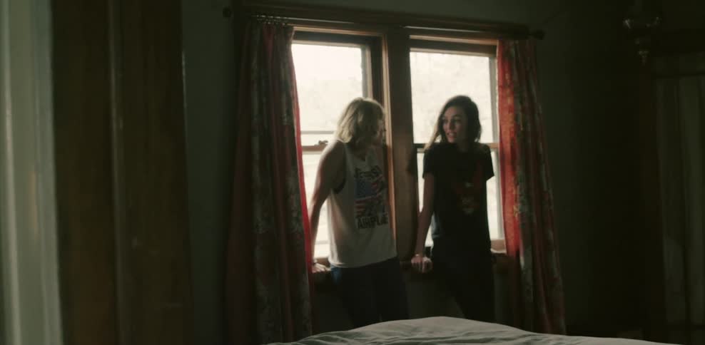 Two women standing next to a window talking
