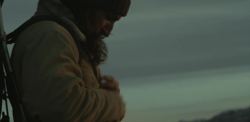 A bearded man adjusts his backpack