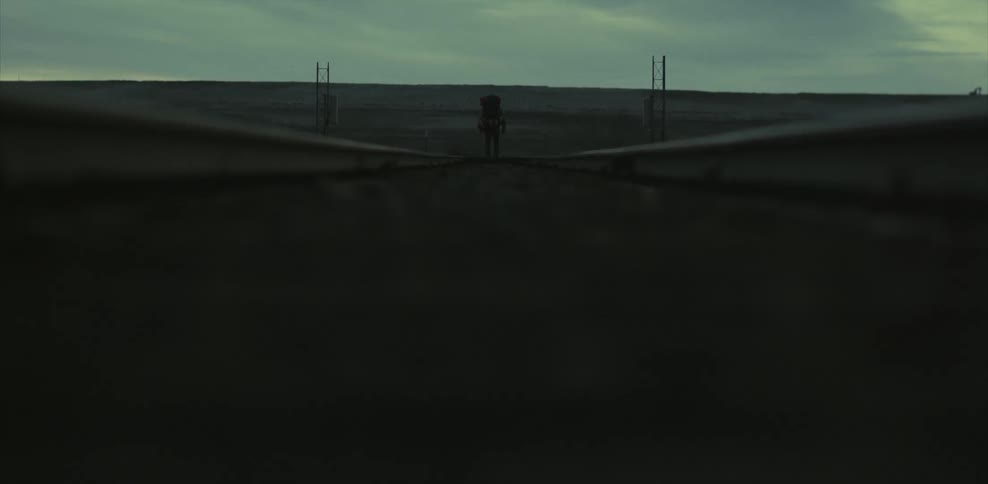 Person walking down railroad tracks on a cloudy day