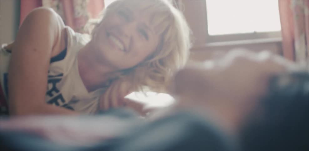 Two women lay in bed smiling and talking