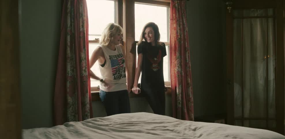 Two women standing next to a window talking and smiling