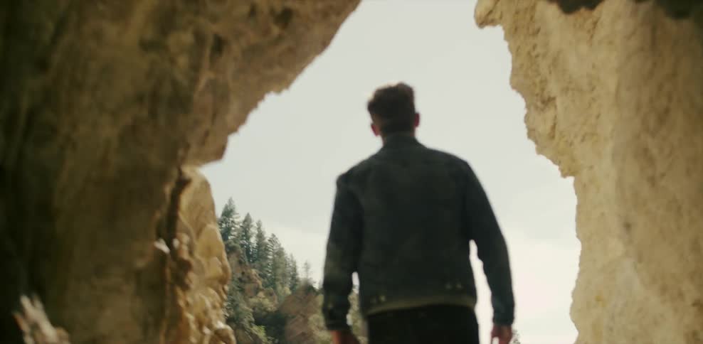 Man walking out of a cave into bright sunlight