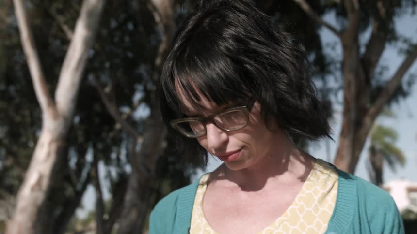 A woman wearing glasses walks on a sunny day